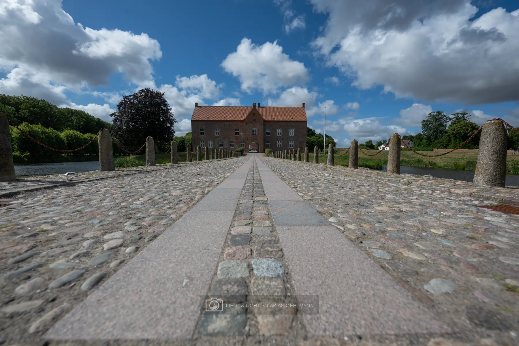 Stone road leading toward a historic building under dramatic clouds