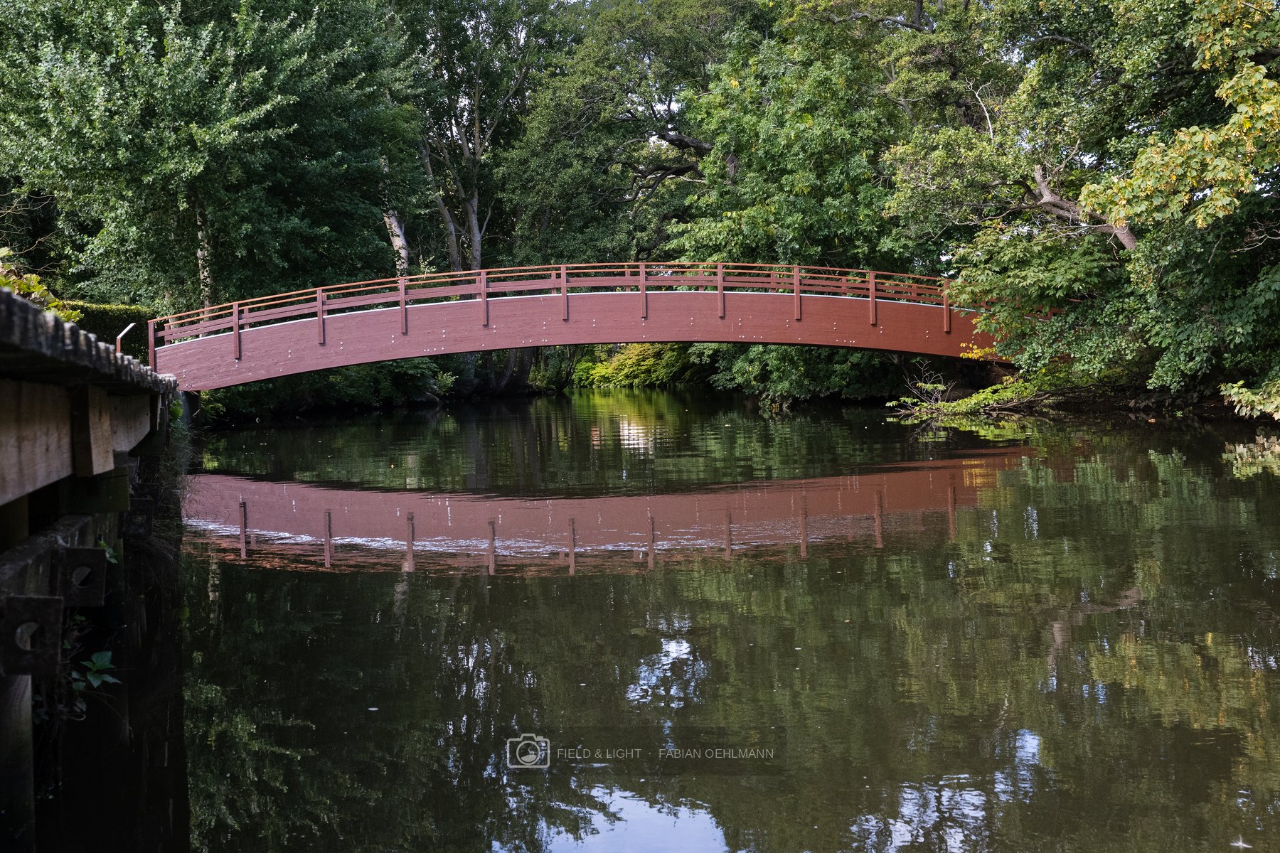 A red footbridge reflected in the river in Sæby